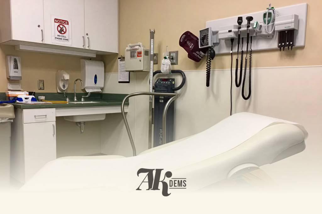 Hospital exam room with cabinets, sink, and wall-mounted medical equipment near a patient bed.
