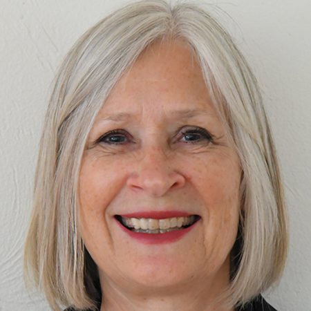 Smiling older woman with shoulder-length gray hair against a light background
