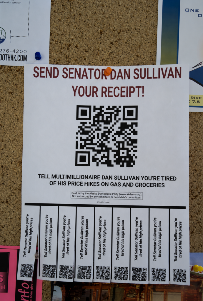 Poster on a corkboard urging viewers to send Senator Dan Sullivan their receipt about price hikes, featuring a large QR code.