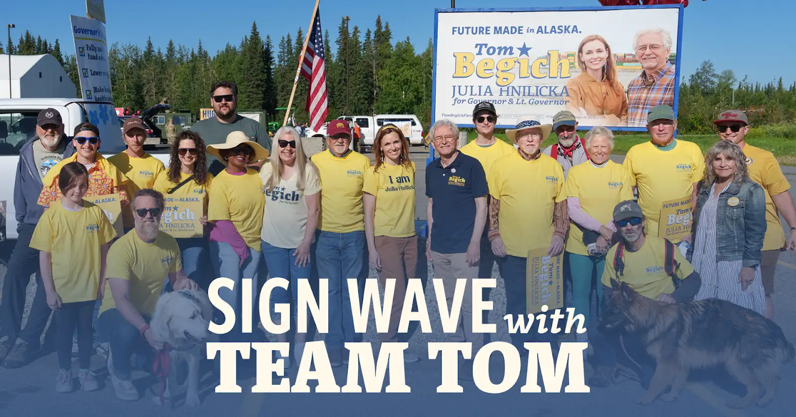 Group of campaign supporters in yellow shirts posing outdoors with a large Alaska banner for Tom Begich and Julia Hinlicka.