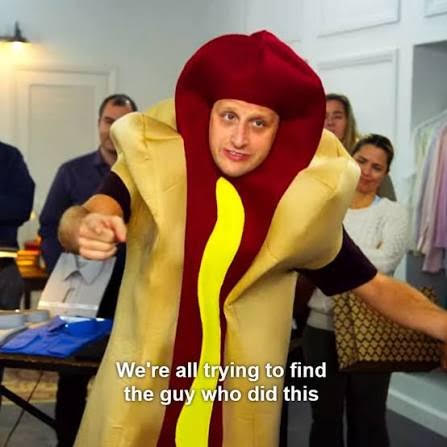Person in a hot dog costume points at the camera at a party; caption reads, "We're all trying to find the guy who did this."